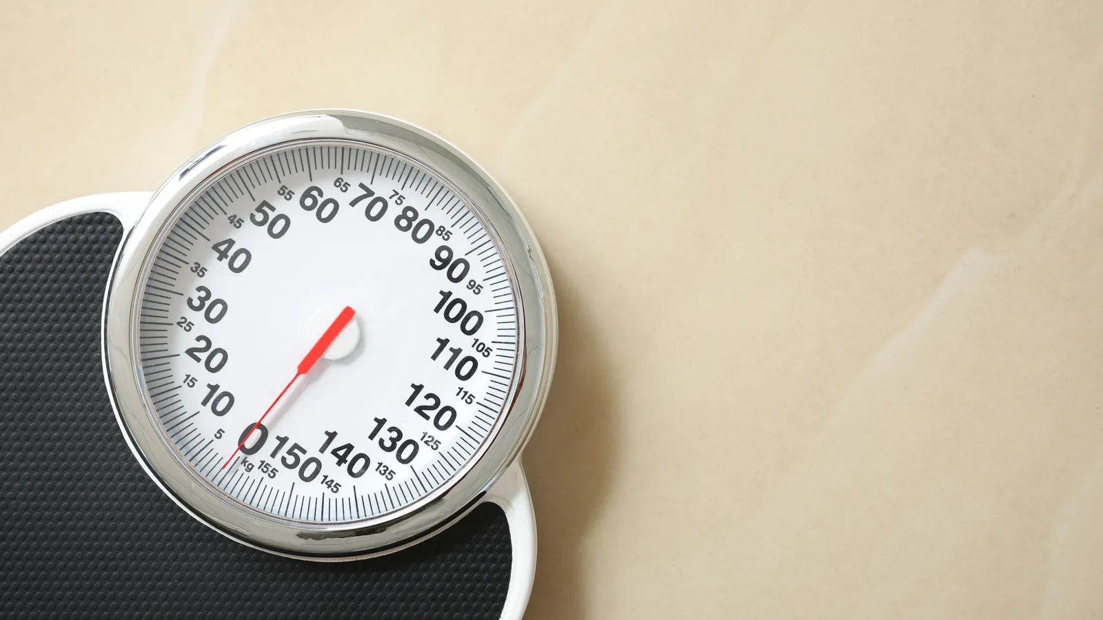 A bathroom scale seen from above on a pale tile floor