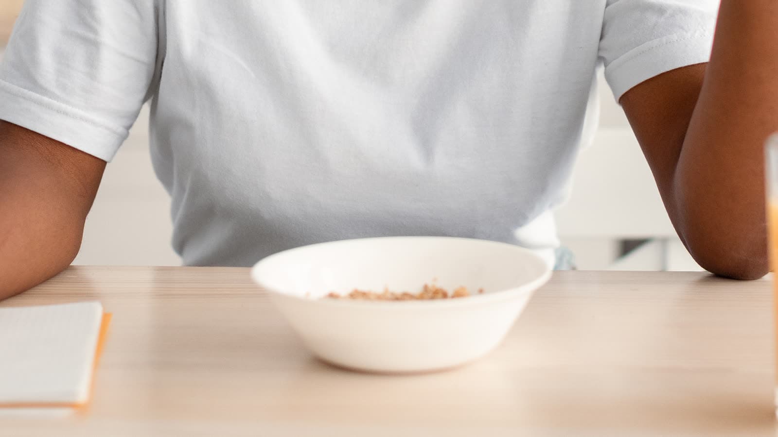 A person sits at a table with a bowl of food.