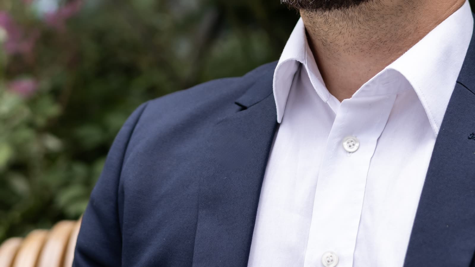 A person in a collared shirt sits outdoors.