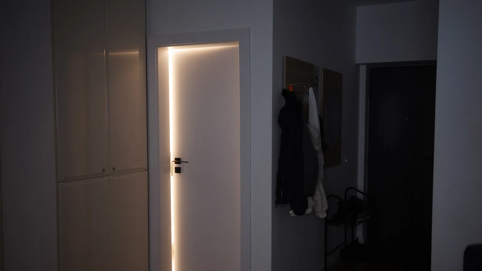Light glowing around the edges of a closed white door in a dark hallway