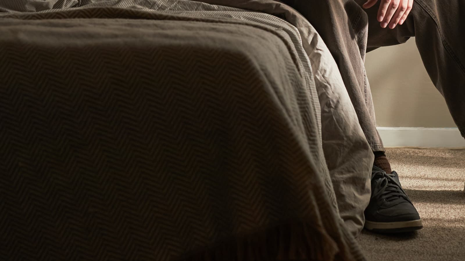 A person sits on the edge of a bed.