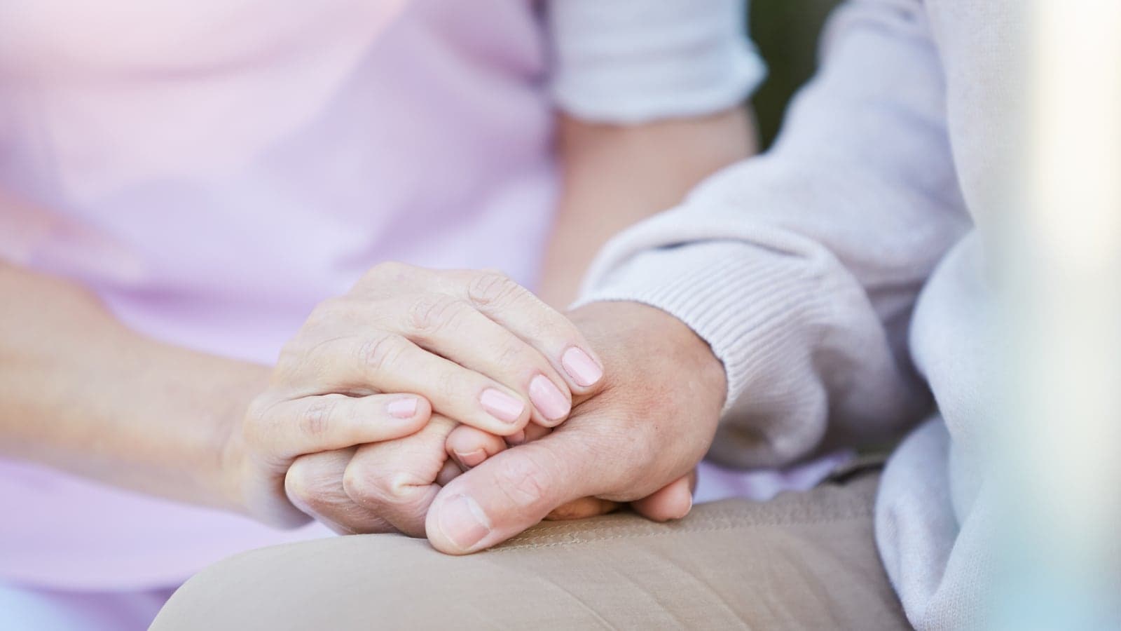 Dos adultos se toman de la mano mientras están sentados juntos en casa.