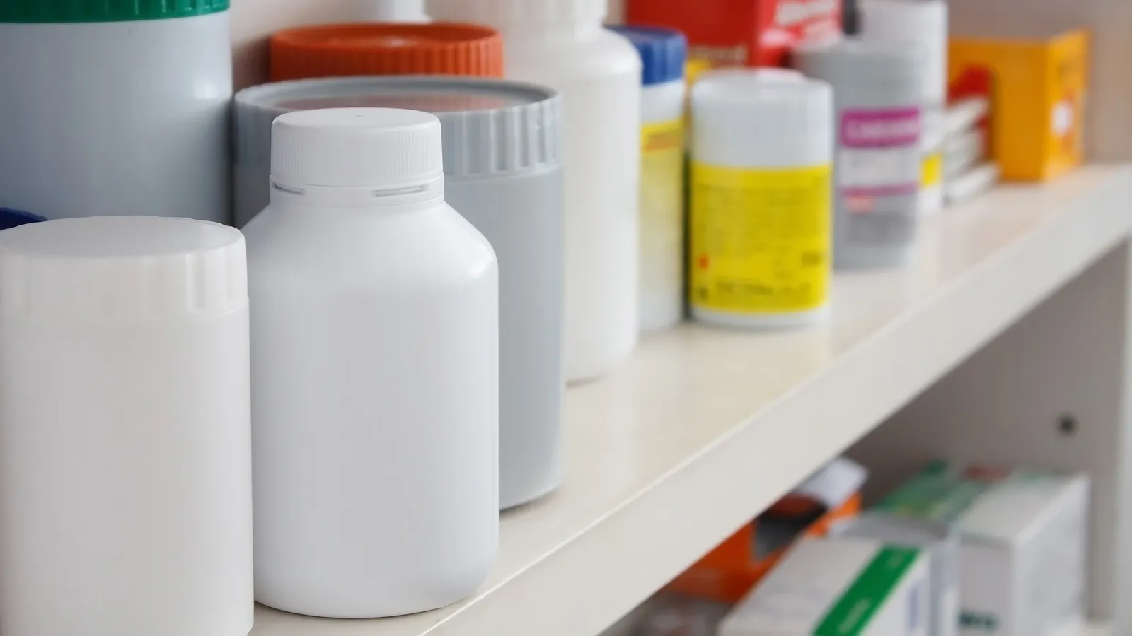 Rows of white medicine bottles on a drugstore shelf