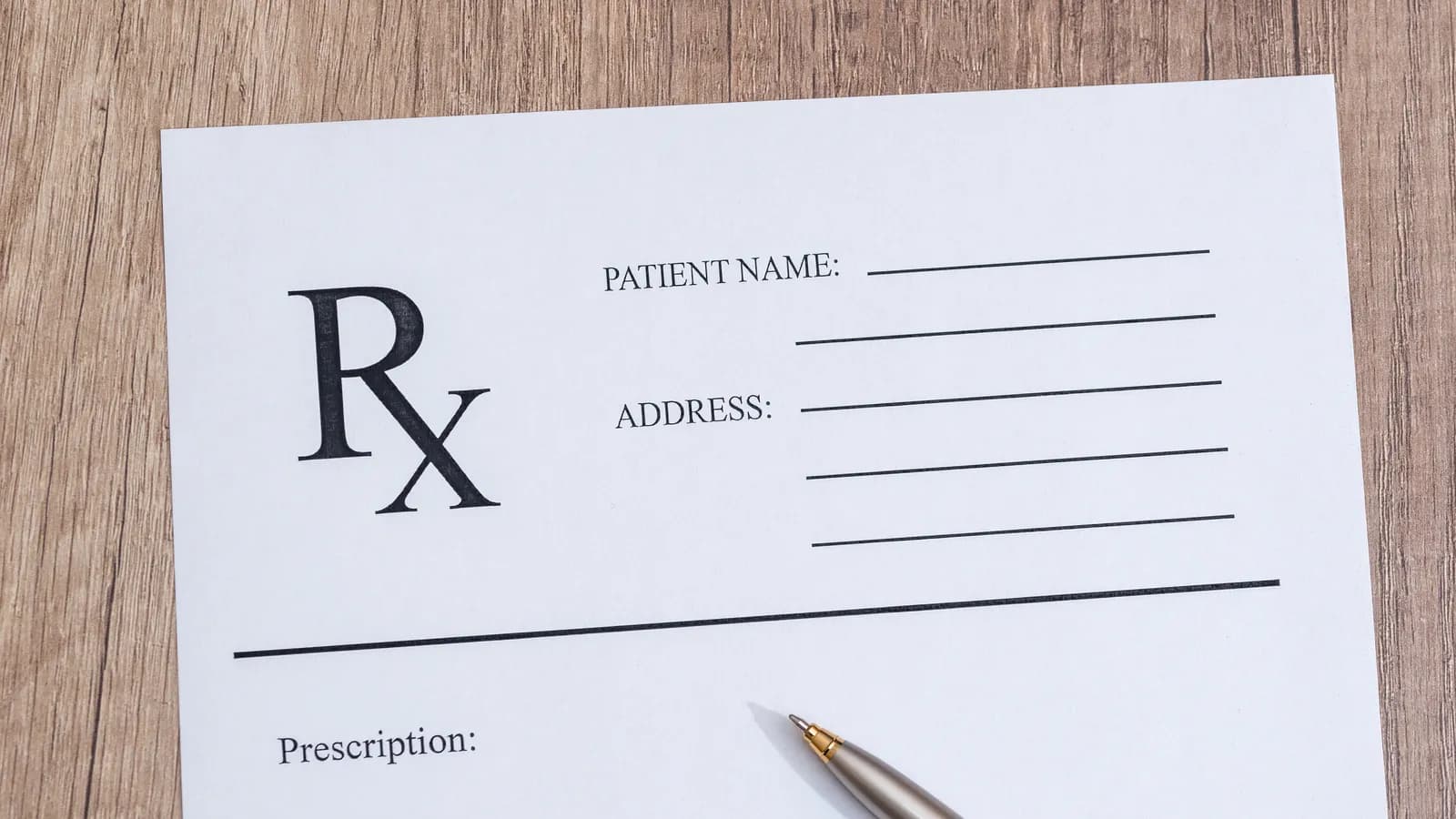 A blank prescription pad with a pen on a wooden desk