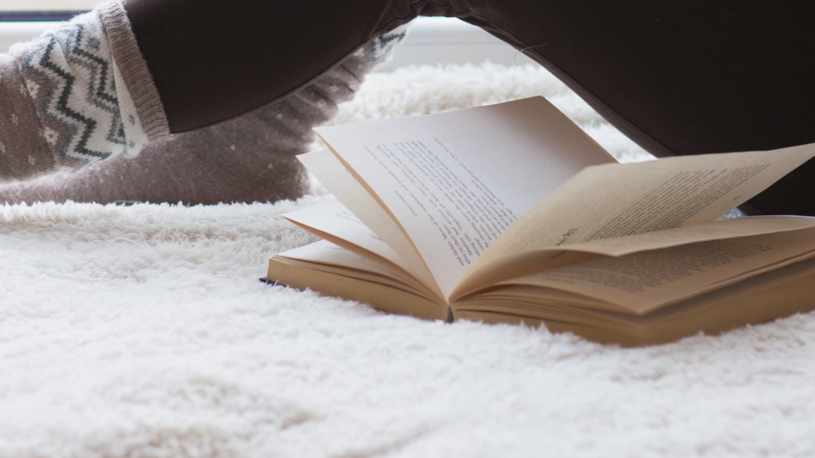 Un libro abierto descansa sobre una manta cerca de una ventana.